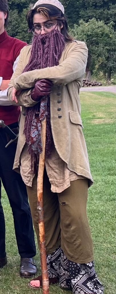 Costume of a stooped old traveller with long grey beard, shawls and walking stick