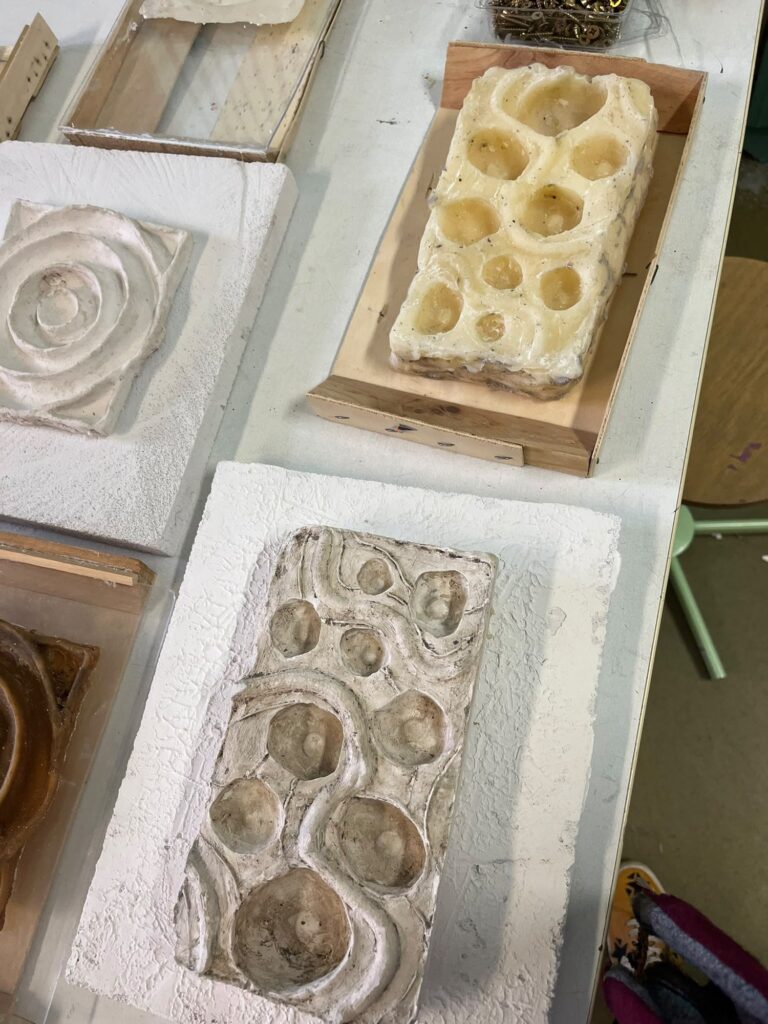 Two plaster relief casts with deep round hollows on a workbench
