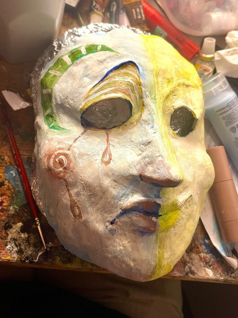 Mask split down the middle in green and yellow with a copper tear