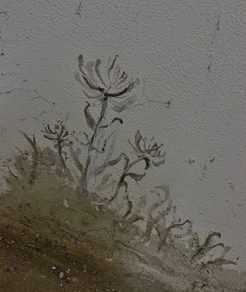 Painted plants rising out of the textured base of a wall